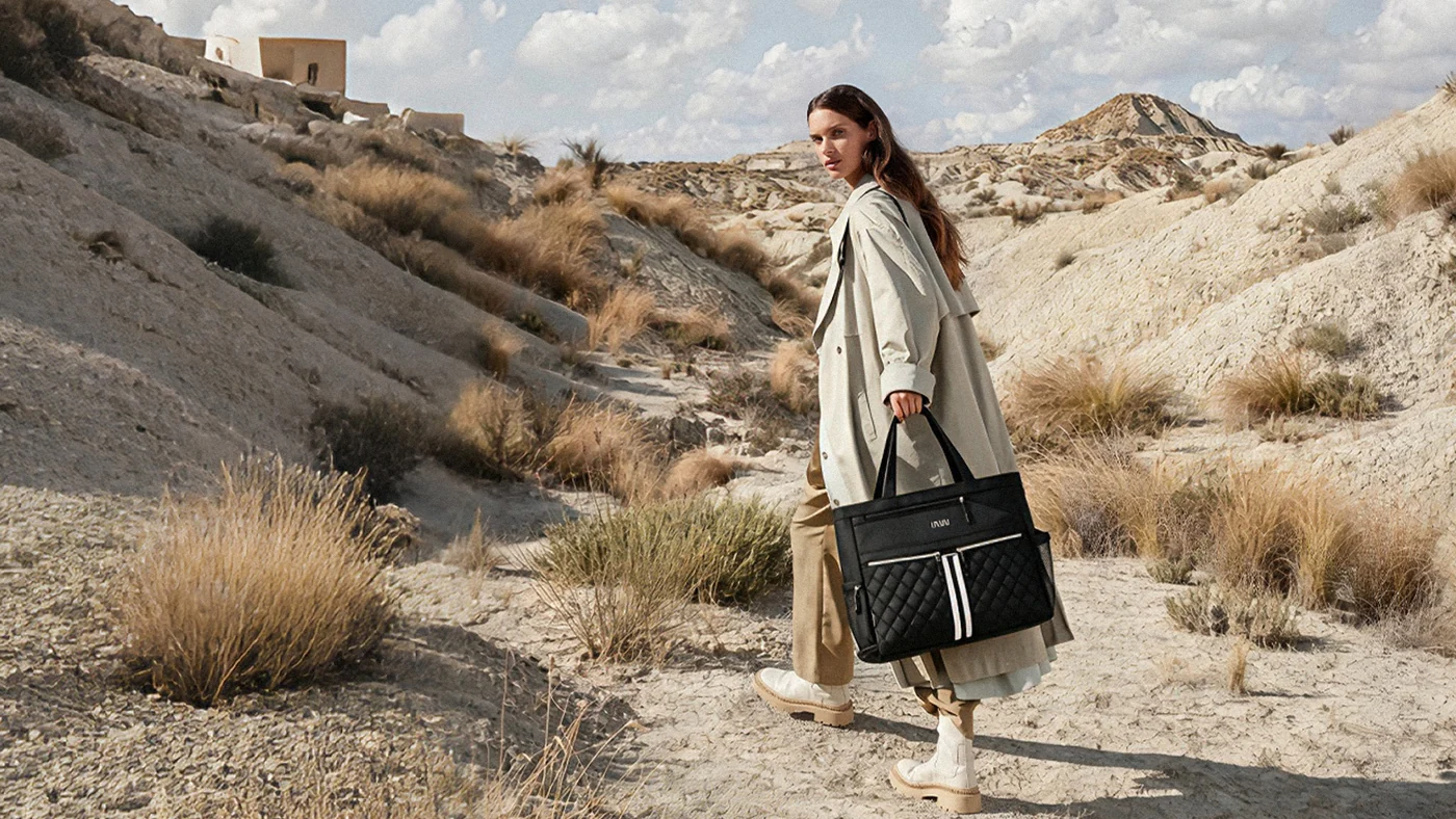 Woman carrying a black NST Tennis Tote along a rocky trail