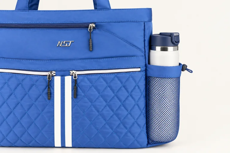 A bottle held in the exterior mesh side pocket of the blue NST Tennis Tote