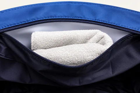 Interior zip pocket holding a folded towel.